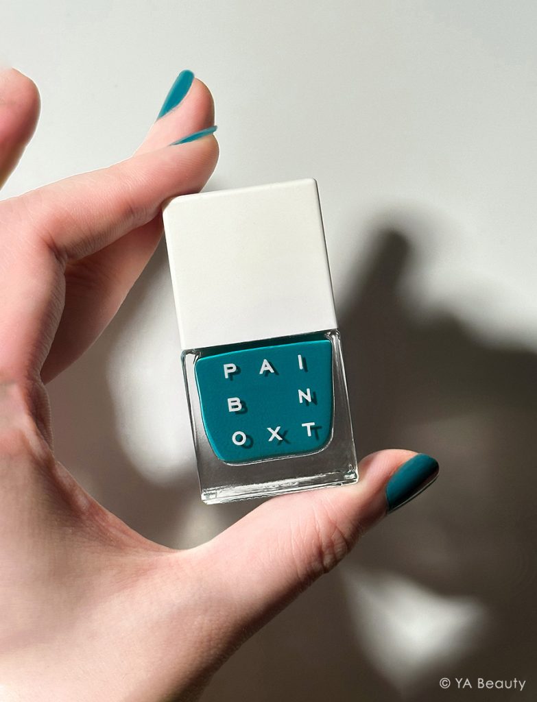 Hand holding Paintbox Nail Lacquer polish in shade Like Satin, with nails painted in the same color