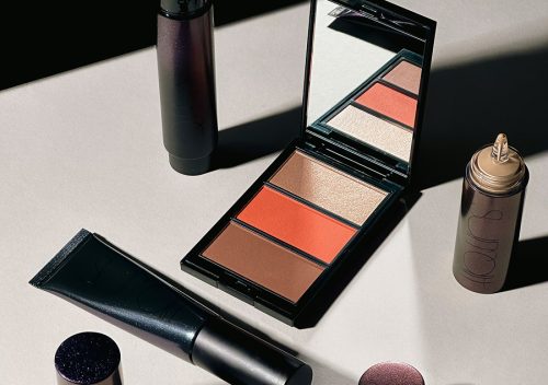 Surratt Beauty flatlay featuring Dew Drop Foundation, Plus de Soleil Blush and Face Palette, Surreal Skin Foundation Wand, and Perfectionniste Primer