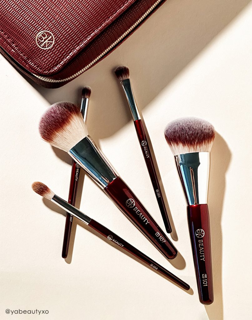 BK Beauty Travel Brush Set featuring the travel version of T101 Contoured Foundation Brush, T107 Flat Blush Brush, T202 Defined Crease Brush, T203 Eyeshadow Shader Brush, and T207 Pencil Blender Brush, as well as a vegan leather pouch in oxblood red color
