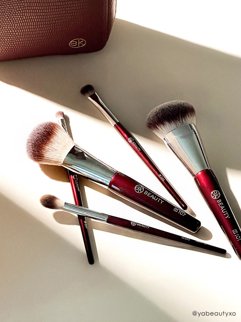 BK Beauty Travel Brush Set featuring the travel version of T101 Contoured Foundation Brush, T107 Flat Blush Brush, T202 Defined Crease Brush, T203 Eyeshadow Shader Brush, and T207 Pencil Blender Brush, as well as a vegan leather pouch in oxblood red color